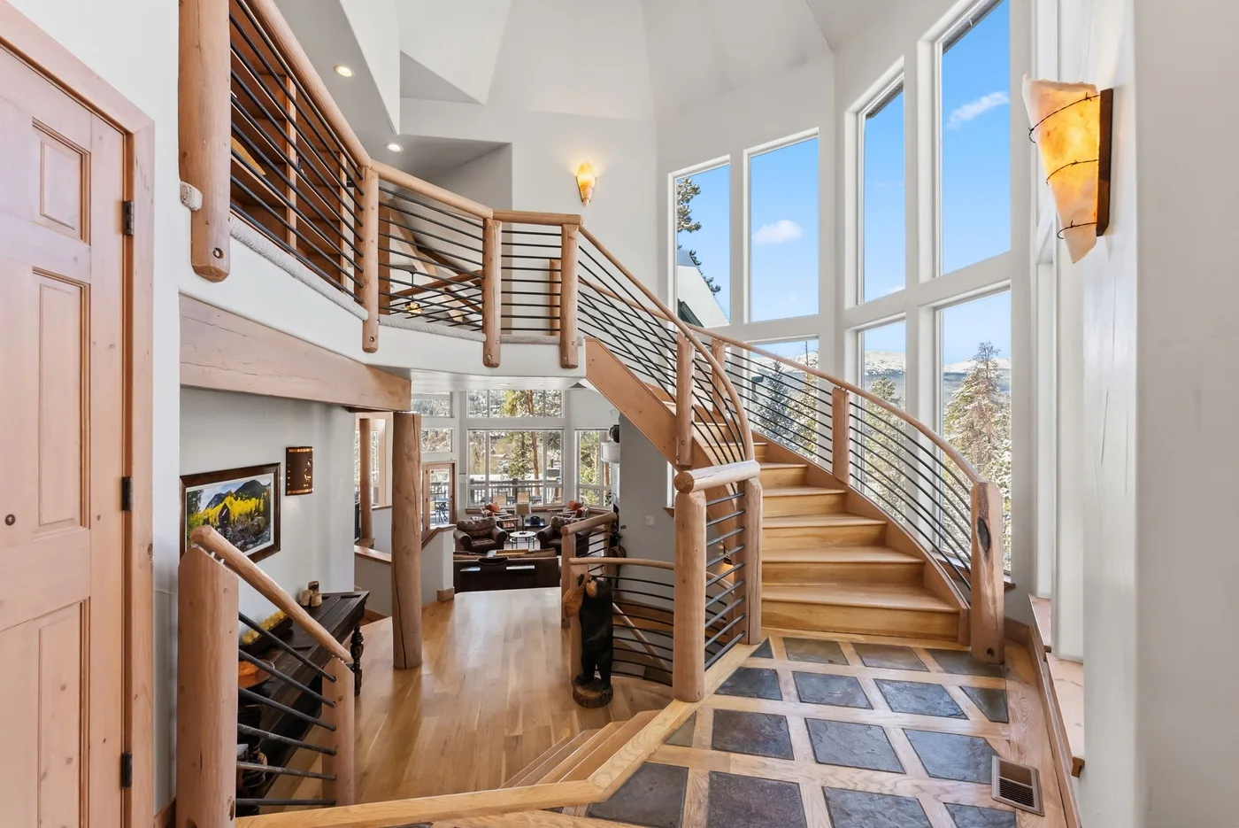 Un interior luminoso de dos alturas tiene una escalera curva y ventanas altas.