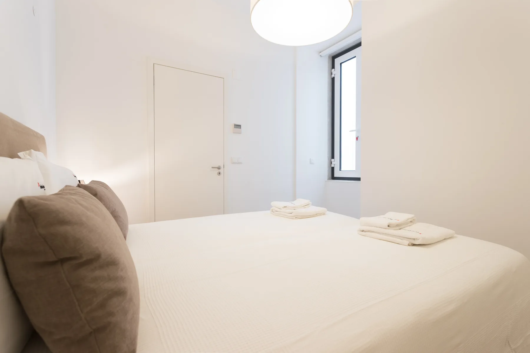 Un dormitorio luminoso con una cama ordenada y toallas dobladas.