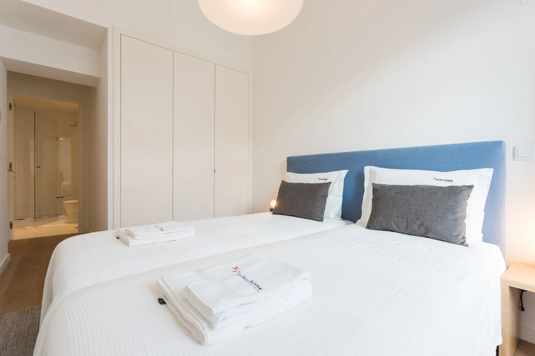 Un dormitorio luminoso con una cama tendida y toallas dobladas.