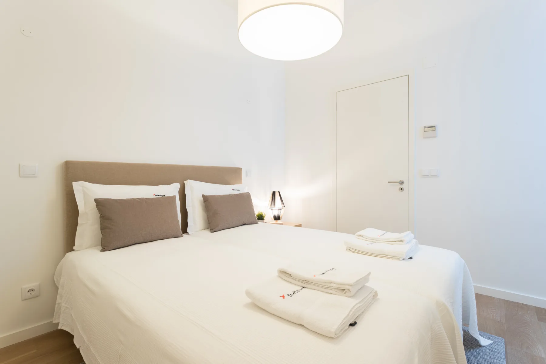 Un dormitorio luminoso con una cama hecha y toallas dobladas.