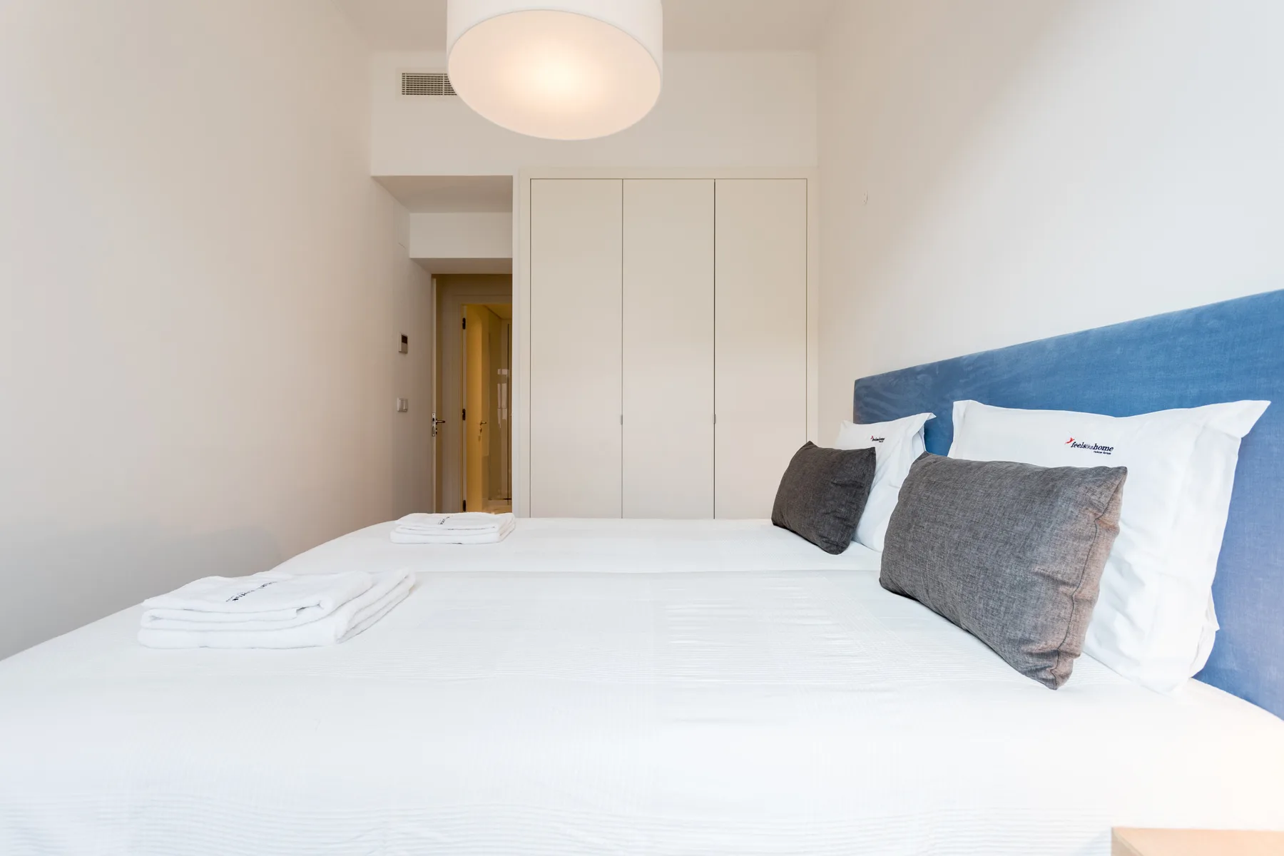 Dormitorio con una cama bien hecha y un cabecero tapizado azul.