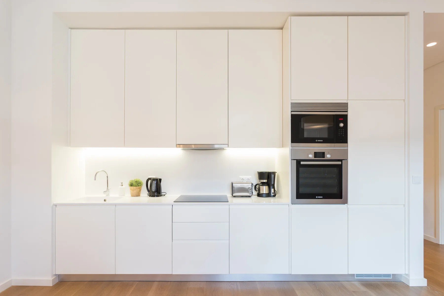 A bright modern kitchen with white cabinets and built-in appliances.