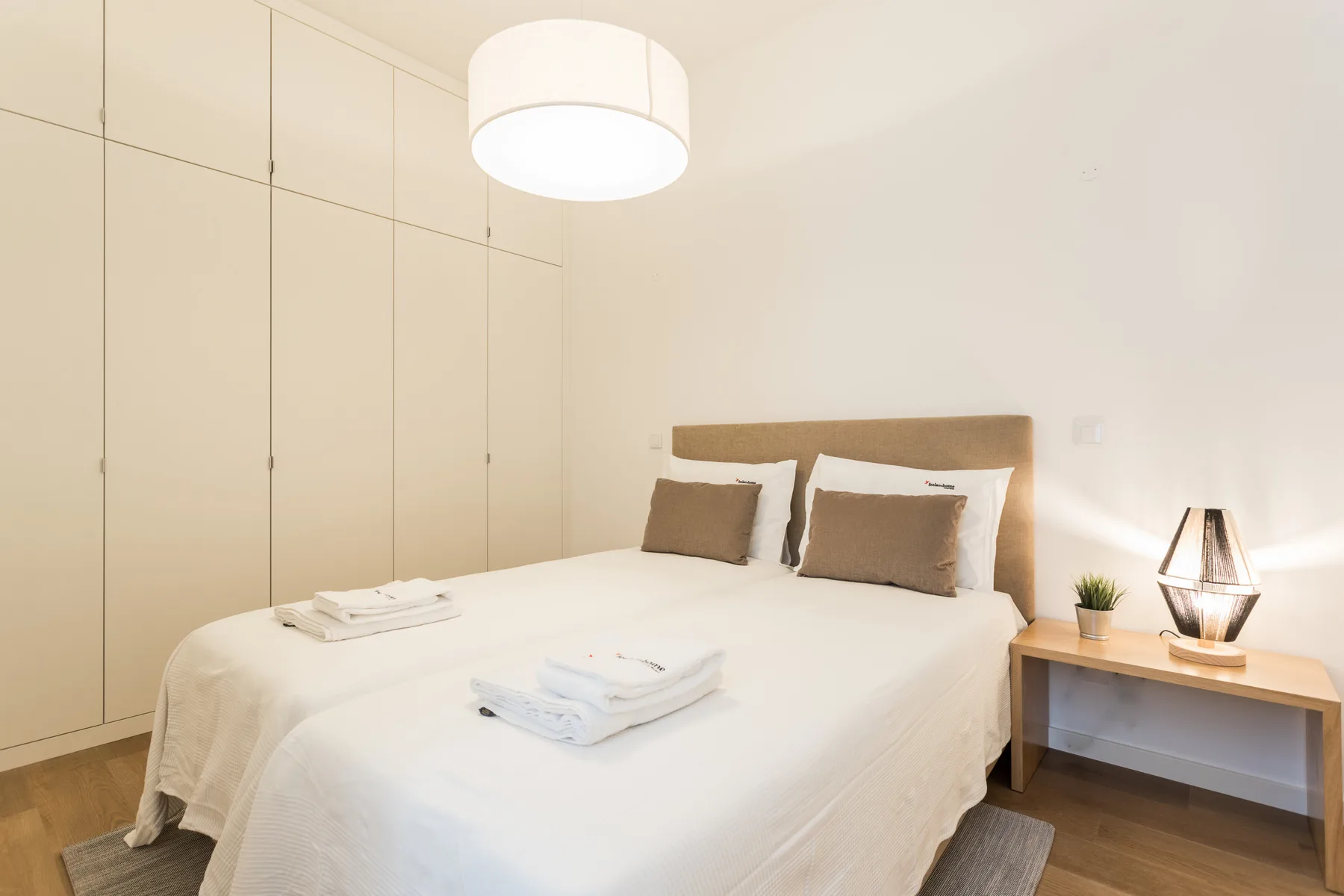 A bright bedroom with a neatly made bed and bedside table.