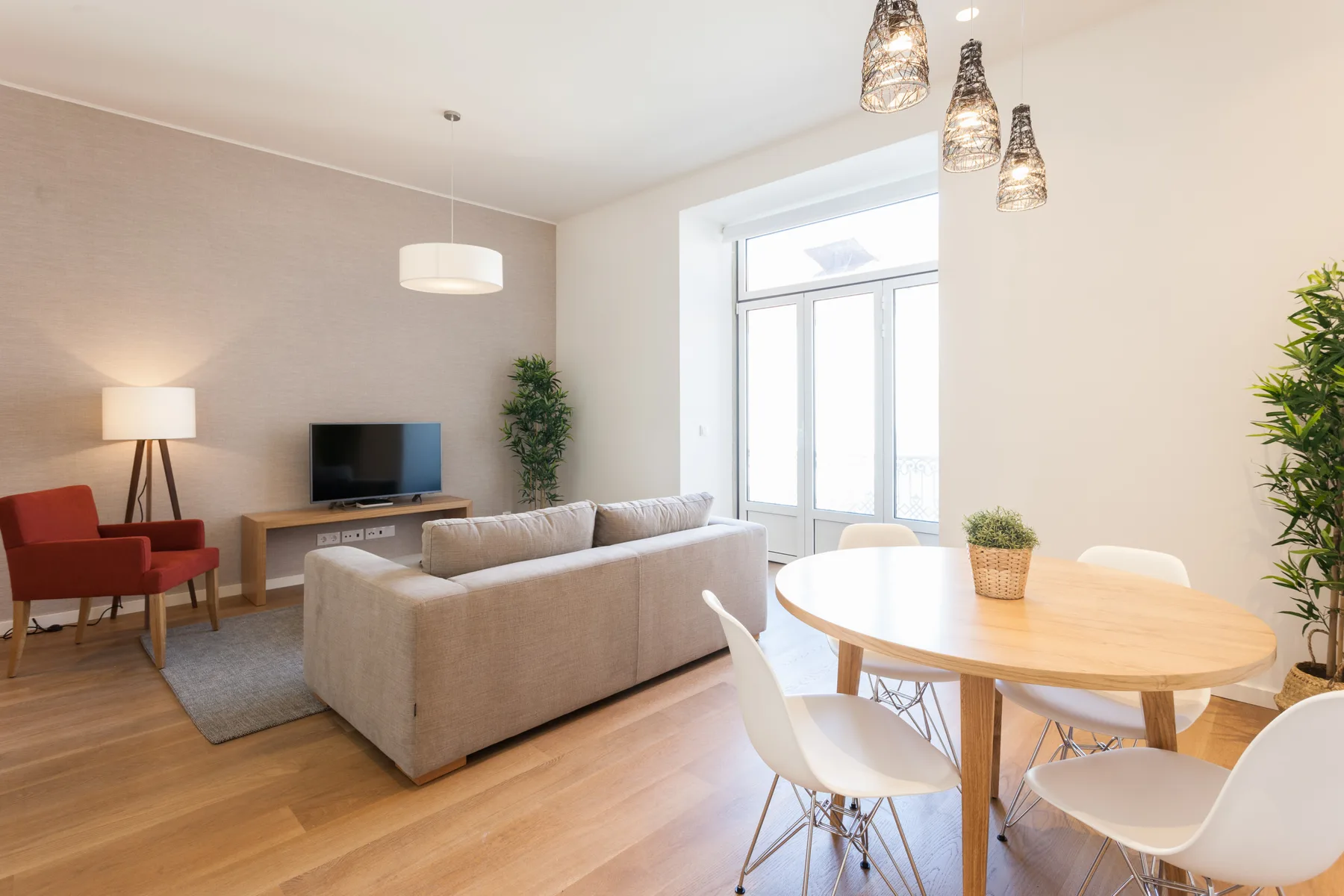 Una luminosa sala de estar y comedor con asientos, un televisor y una mesa de madera.