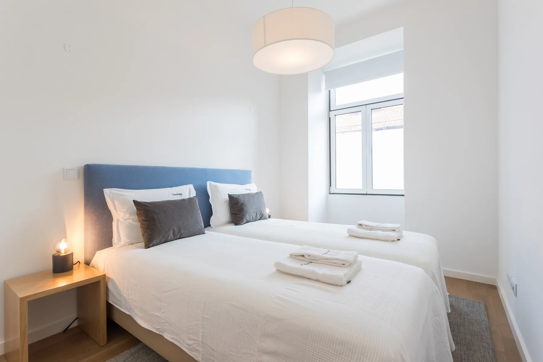 Un dormitorio luminoso con una cama bien hecha junto a una ventana.