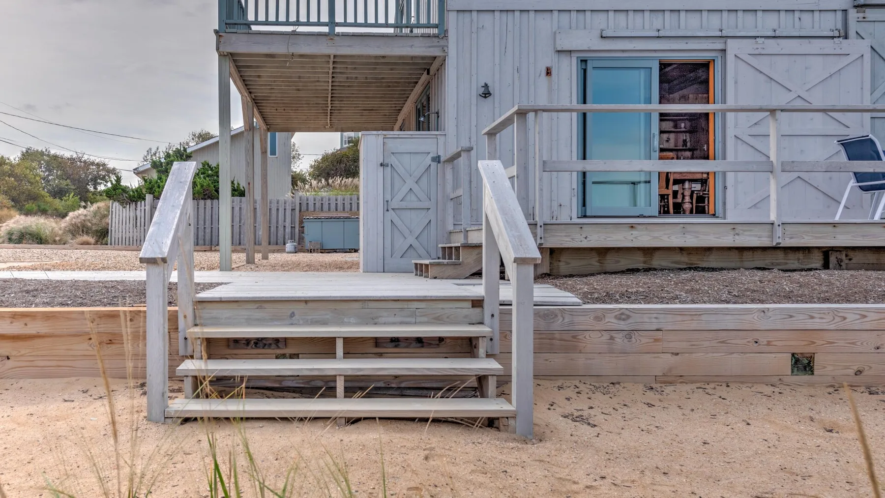 A raised outdoor deck with wooden steps sits beside a light-colored building.