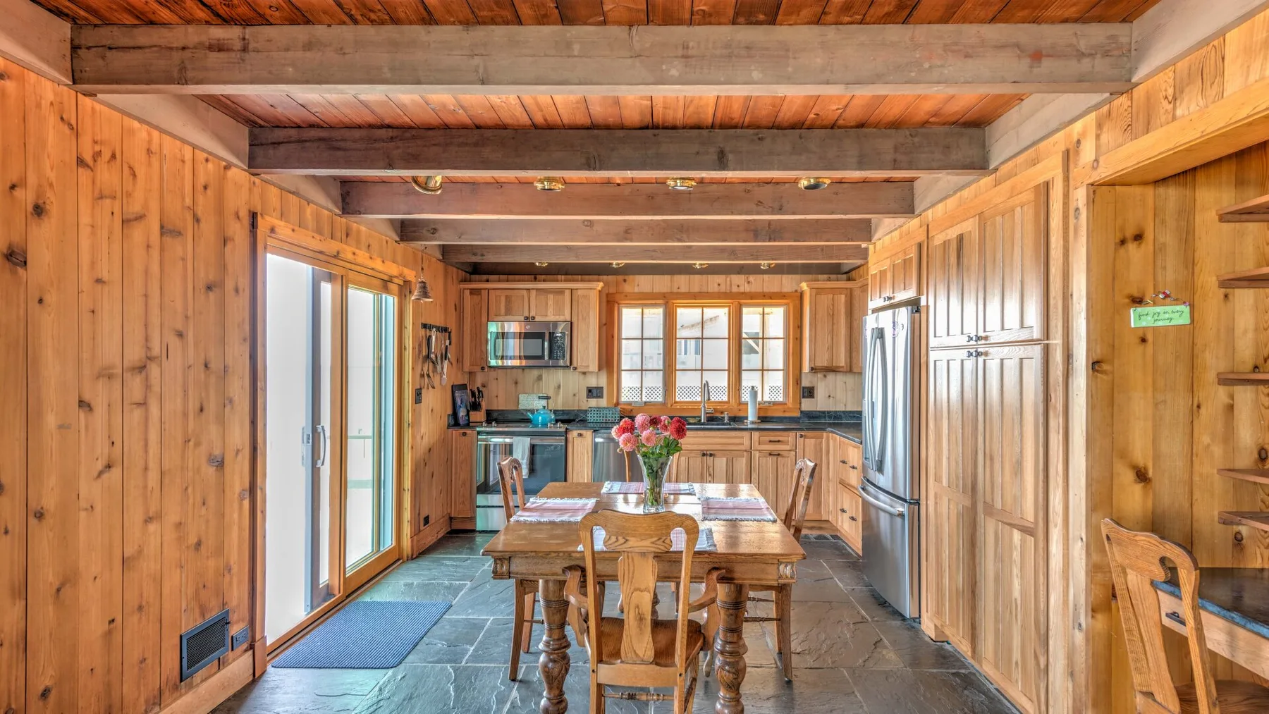 A wood-paneled dining area with a long table set near large windows.