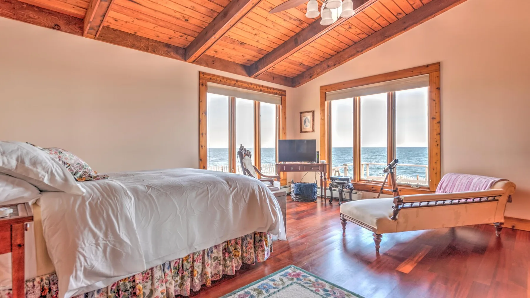 A bedroom with beds, seating, and large windows overlooking the water.