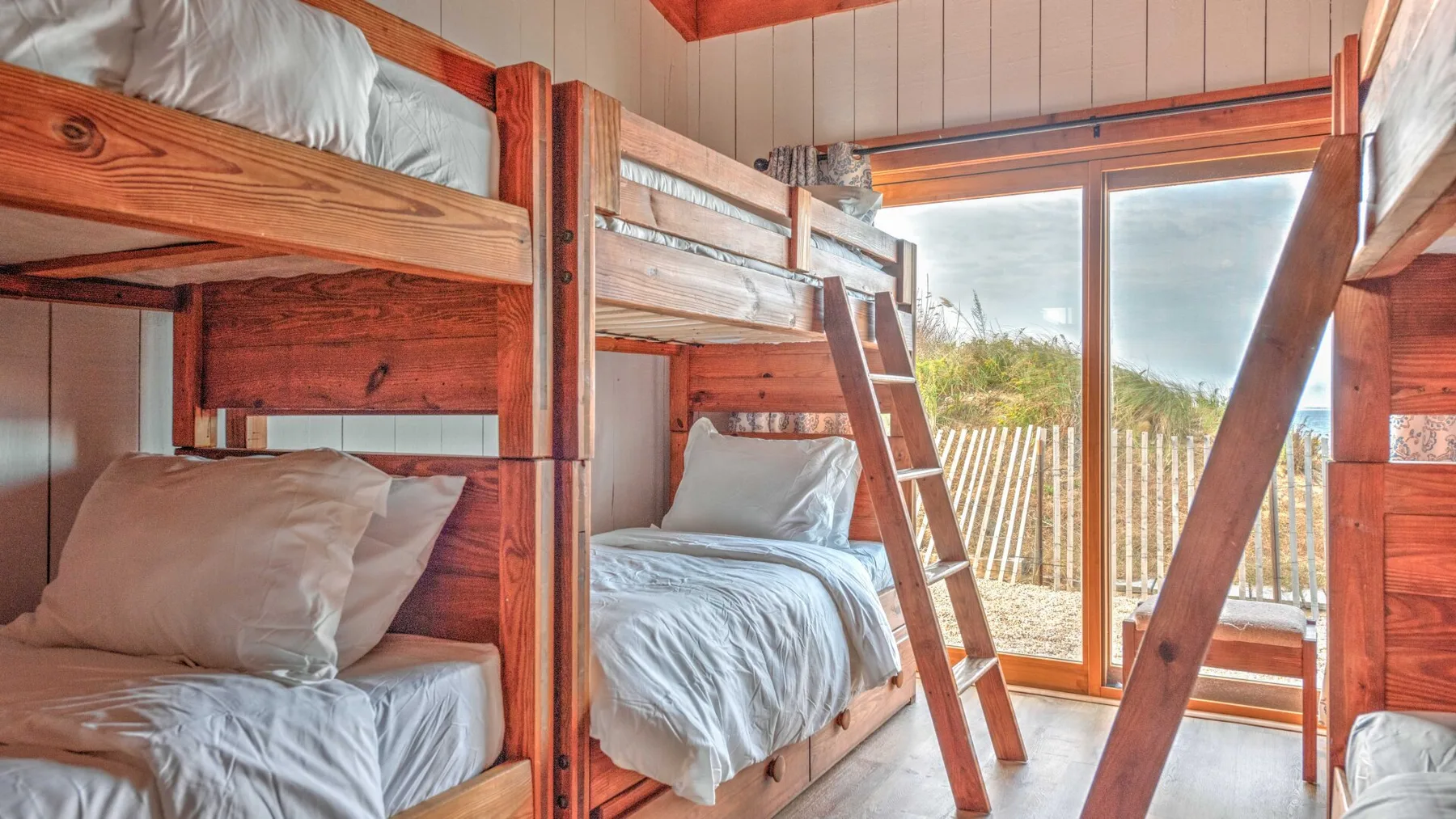 A bunk bedroom with wooden beds and a glass door opening onto a balcony.