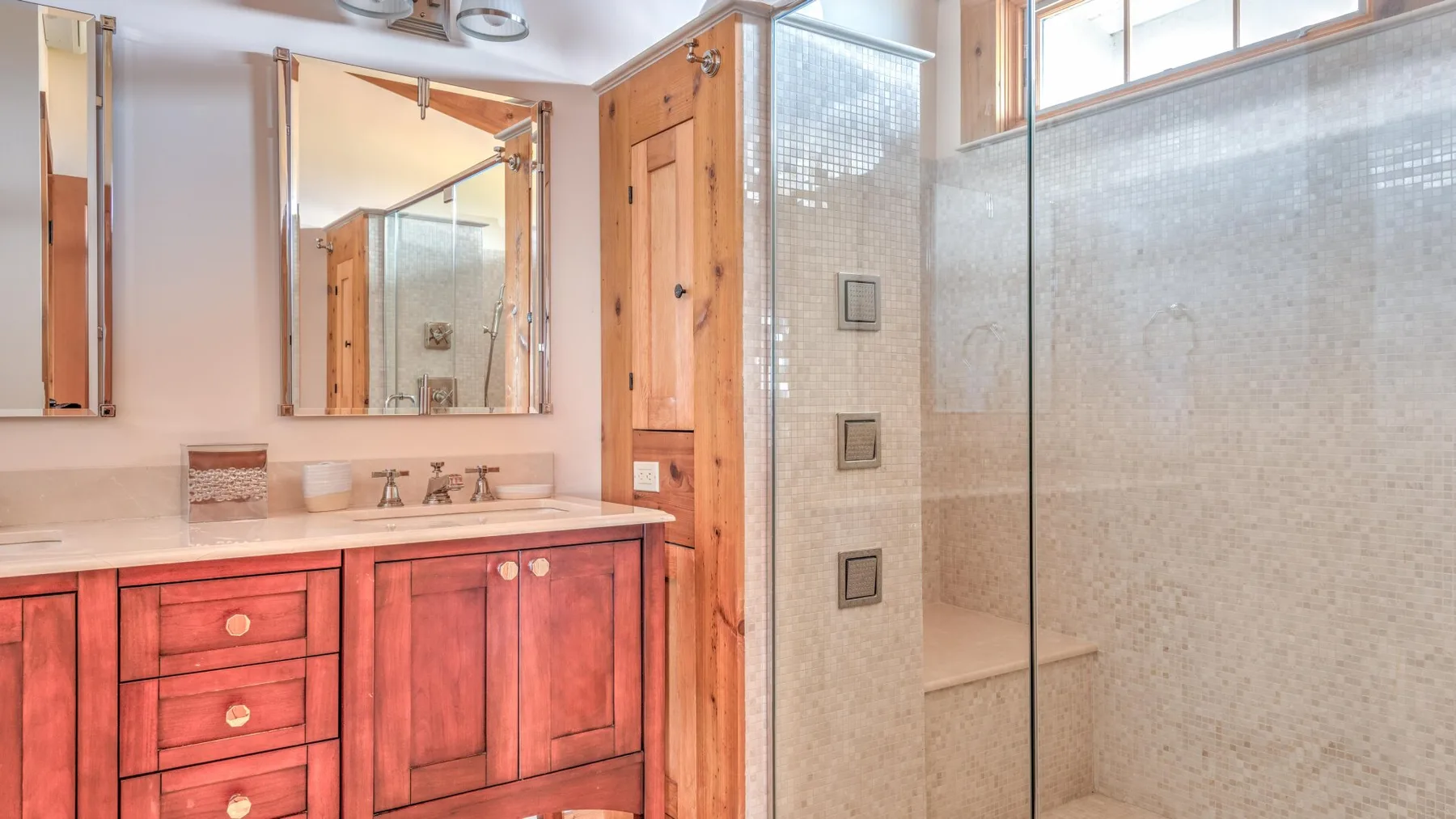 A bathroom vanity with a mirror stands beside a glass-enclosed shower.
