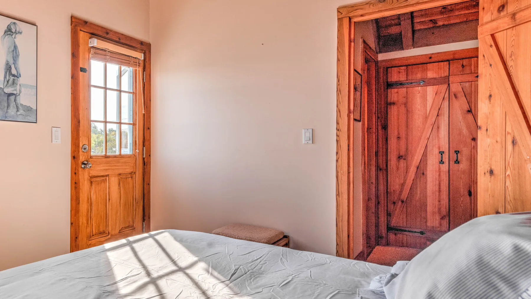 A bedroom with a wooden entry door and a bed in the foreground.