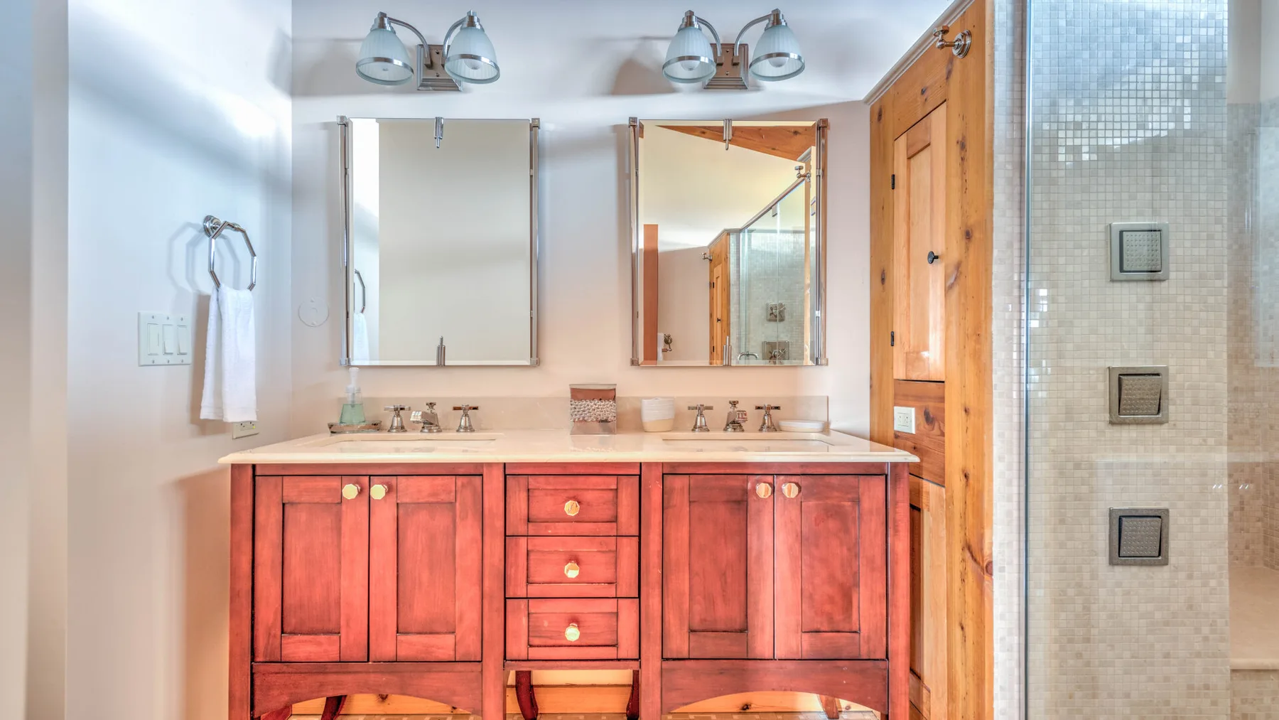 A bathroom vanity with two sinks, mirrors, and wooden cabinetry.