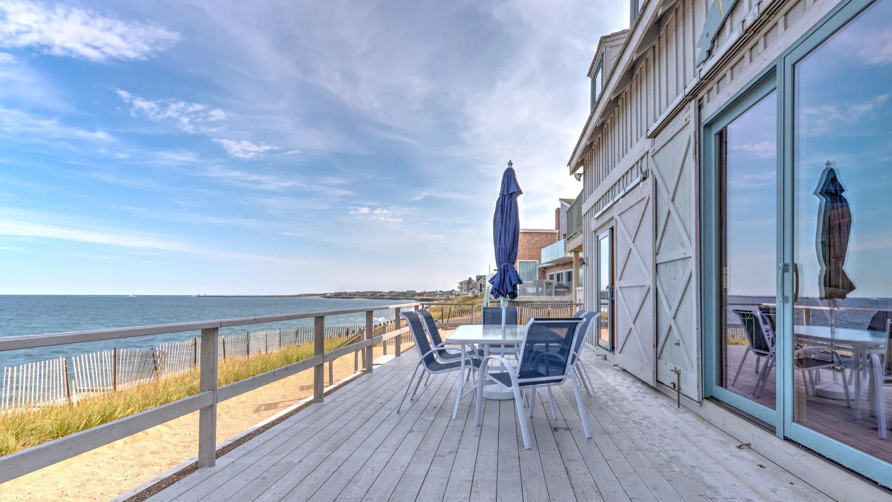 A seaside deck with outdoor seating overlooks the water.
