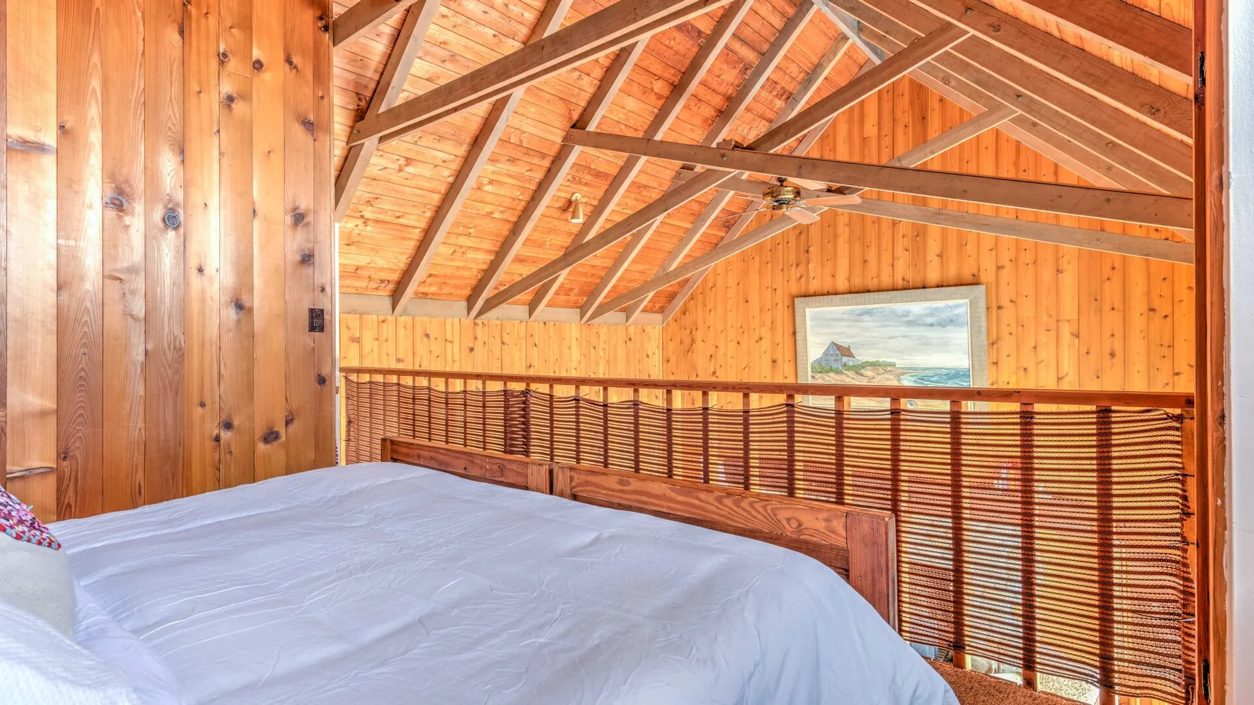 A bedroom with a large bed beneath a sloped wooden ceiling.