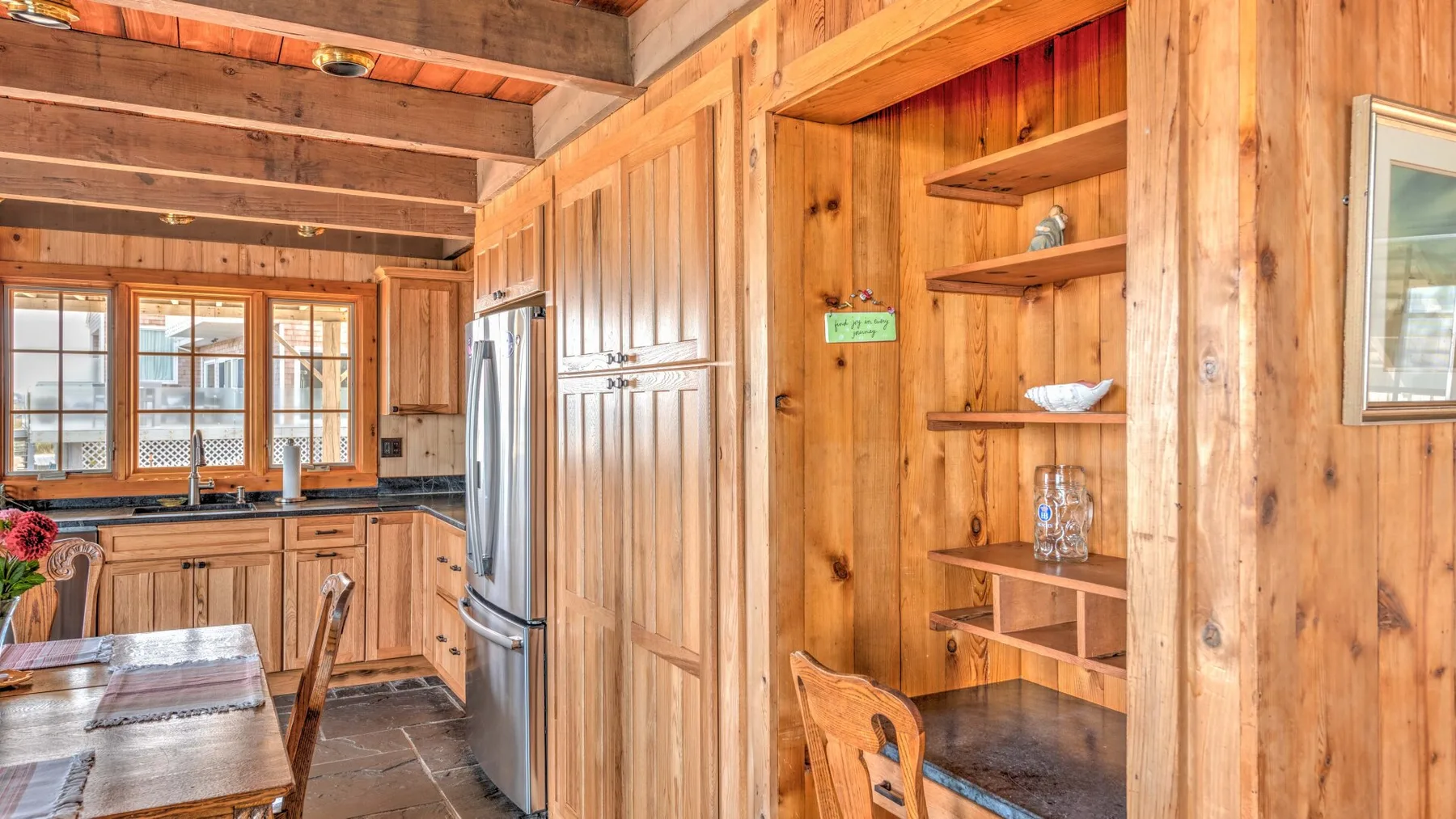 A wood-paneled kitchen with a dining table and stainless steel refrigerator.