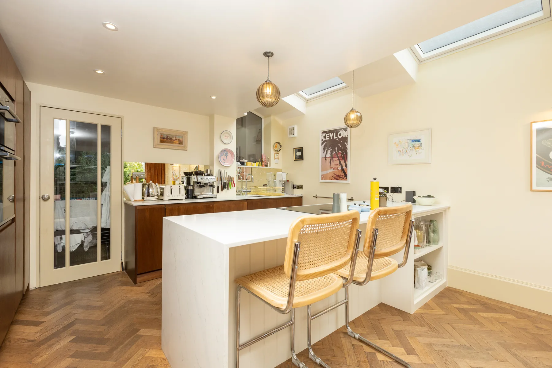 A bright kitchen with a white island and two stools.