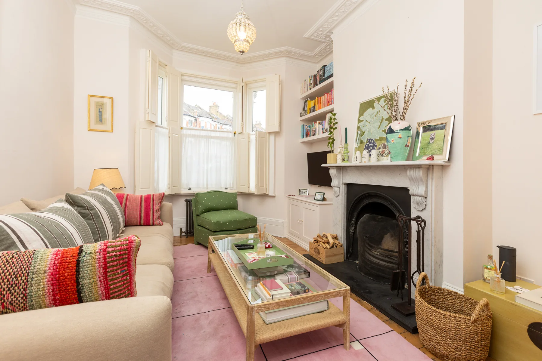 A bright living room with seating, a glass coffee table, and a fireplace.