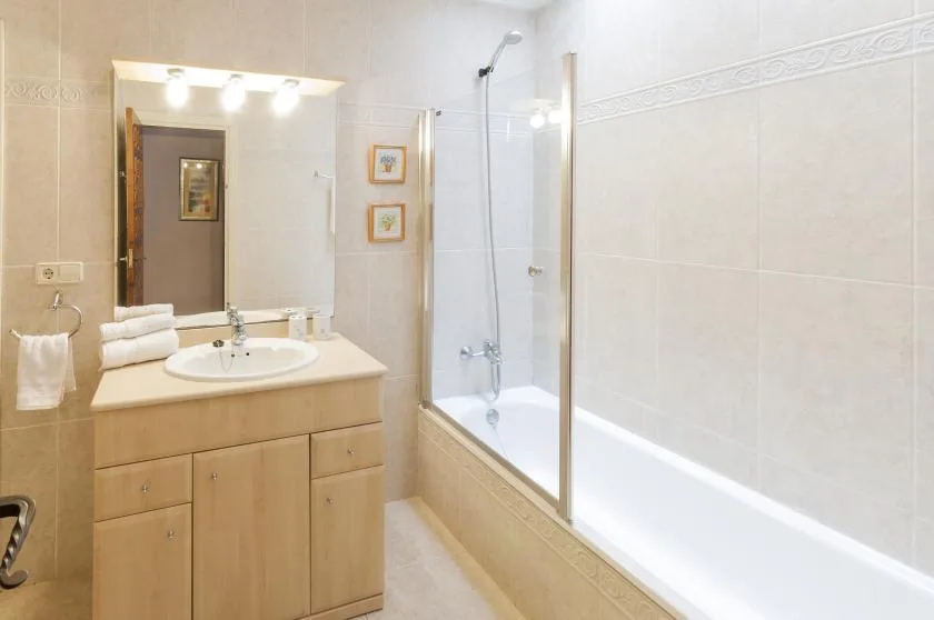 Un baño revestido de azulejos tiene un lavabo junto a una bañera con ducha.