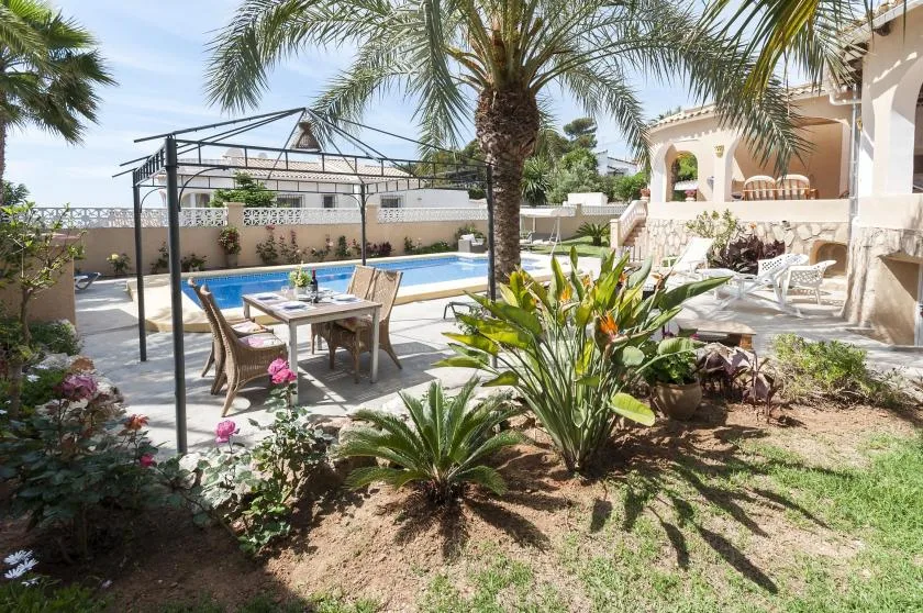 Un patio ajardinado al aire libre con piscina y mesa de comedor.