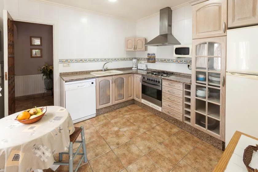 Una cocina luminosa con gabinetes de madera, una estufa y una pequeña mesa de comedor.