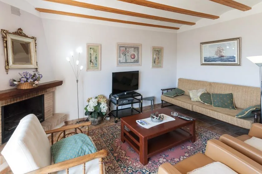 Una sala de estar con asientos alrededor de una mesa de centro y un televisor.