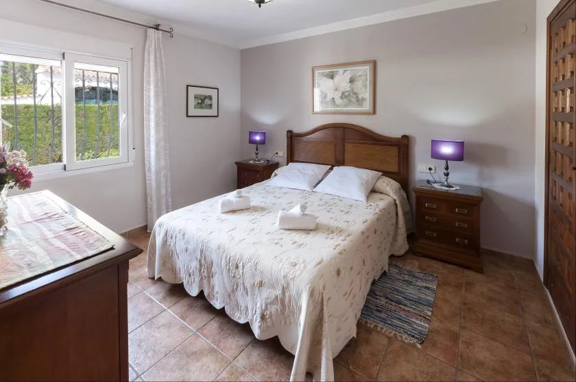 Un dormitorio con una cama doble, mesitas de noche y una ventana.