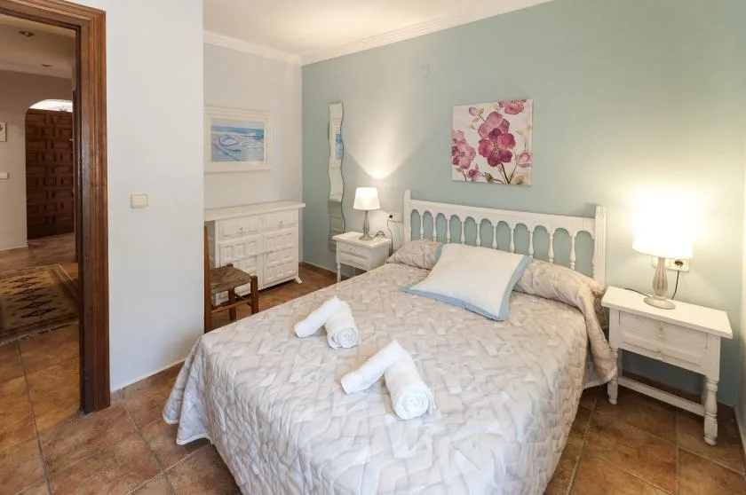 Un dormitorio con una cama, mesitas de noche y un cuadro floral.