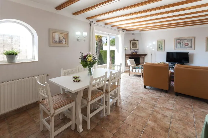 Un comedor y sala de estar con una mesa blanca, asientos y un televisor.