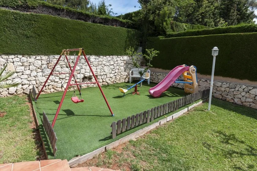 Un parque infantil al aire libre con columpios y un tobogán sobre césped.