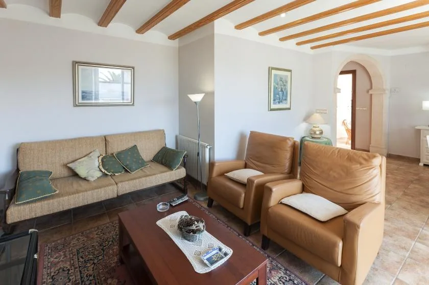 Una sala de estar con un sofá, sillones y una mesa de centro de madera.
