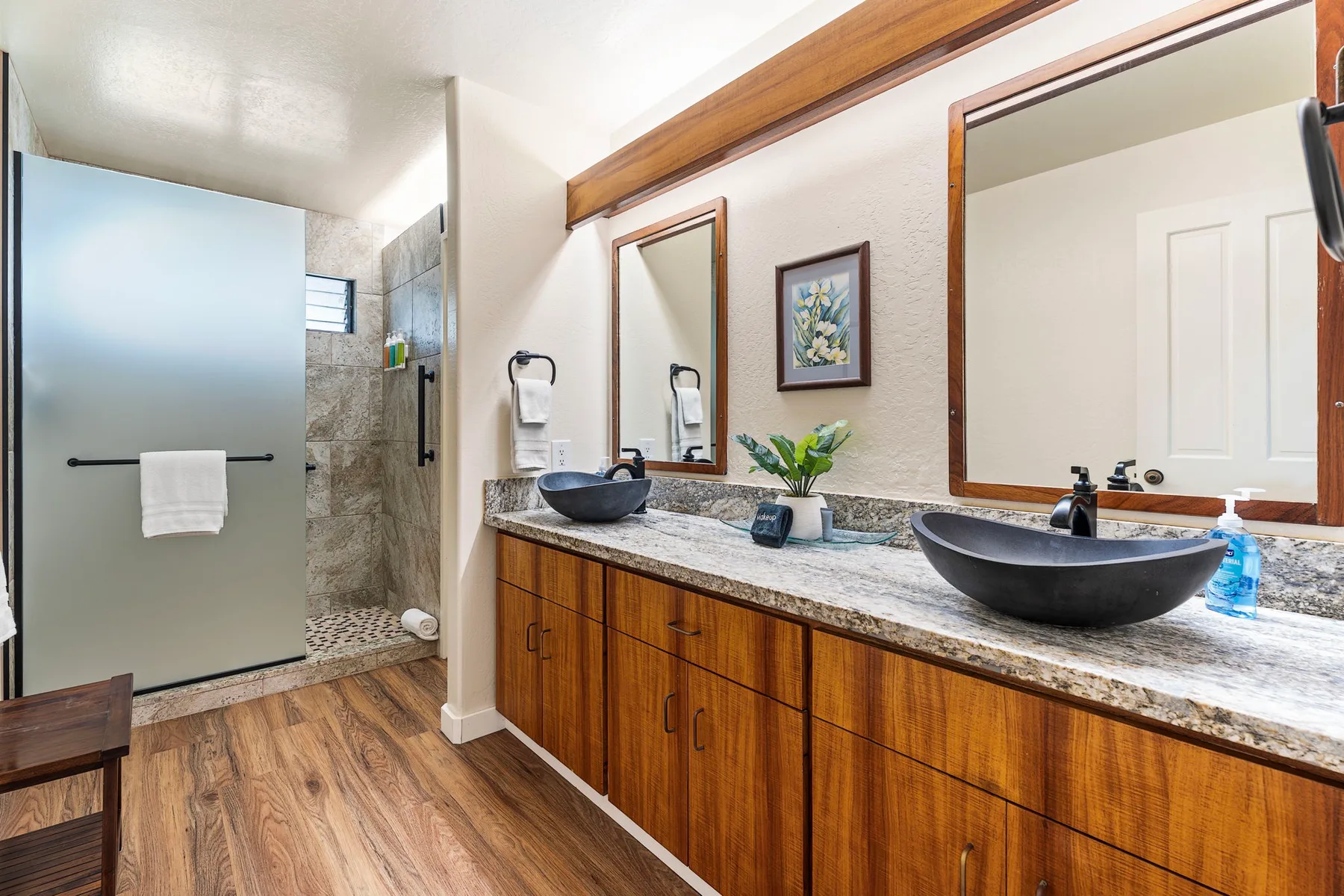 Un mueble de baño con dos lavabos está junto a una ducha de vidrio.