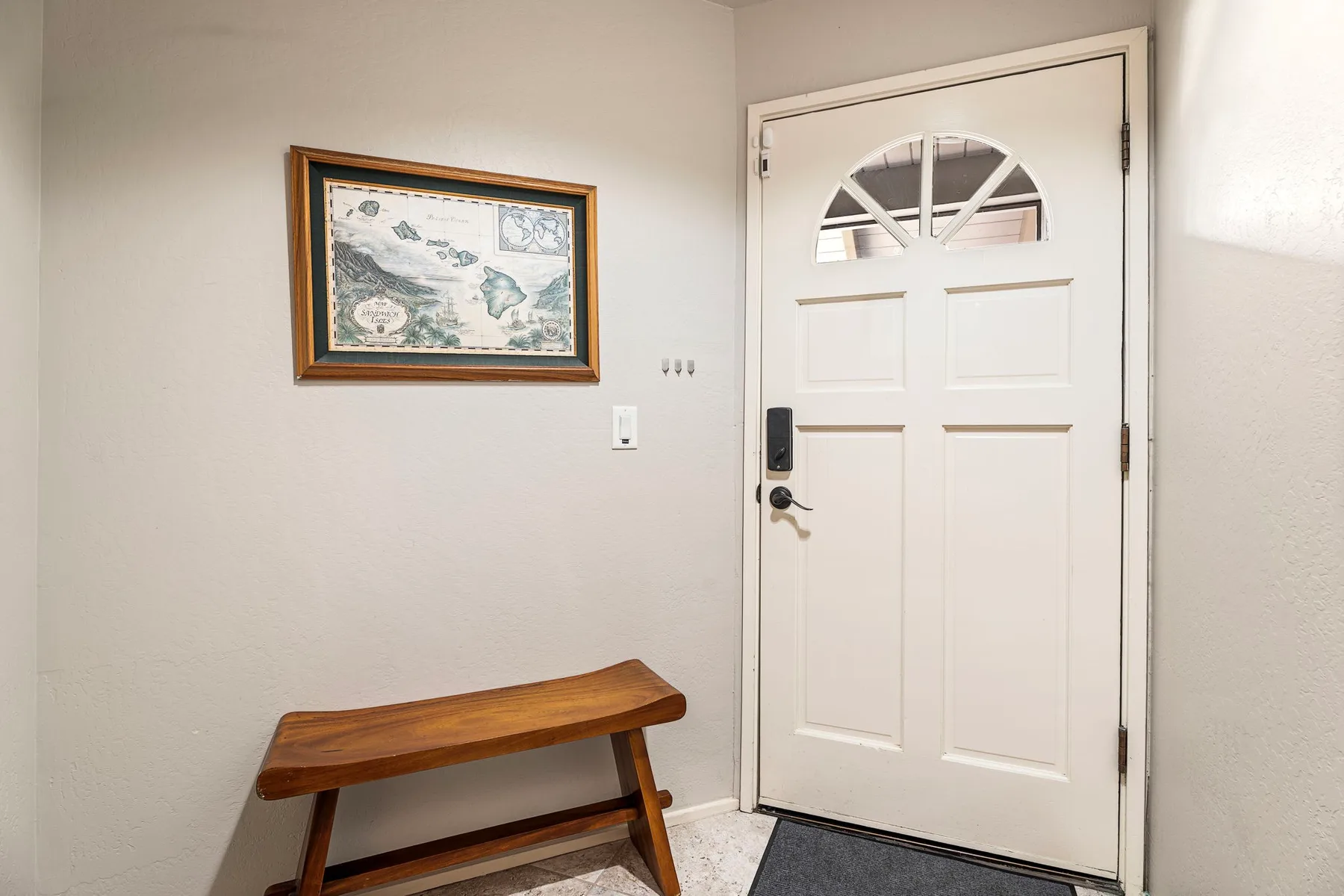Una entrada luminosa con una puerta blanca y un banco de madera.