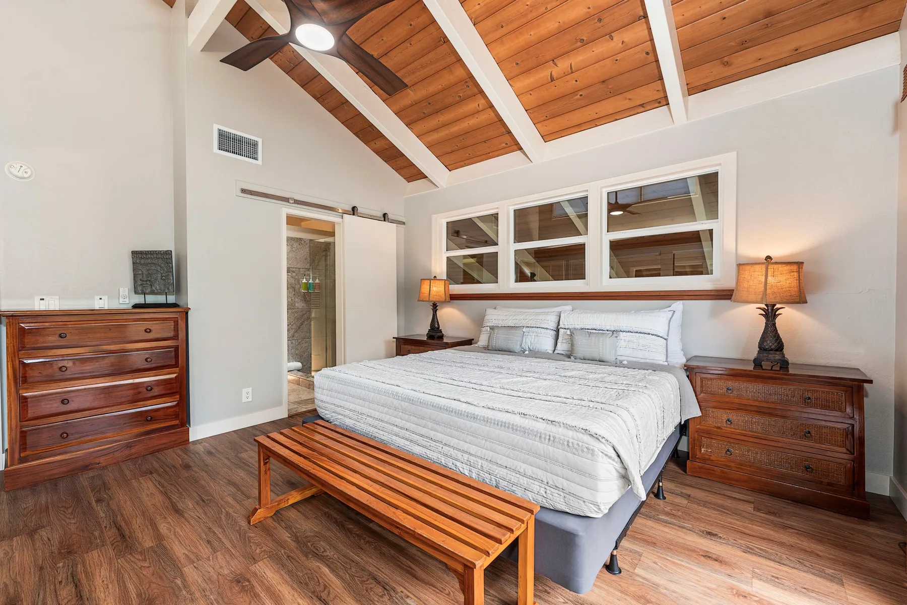 Un dormitorio con una cama grande, un banco de madera y un techo de madera expuesta.