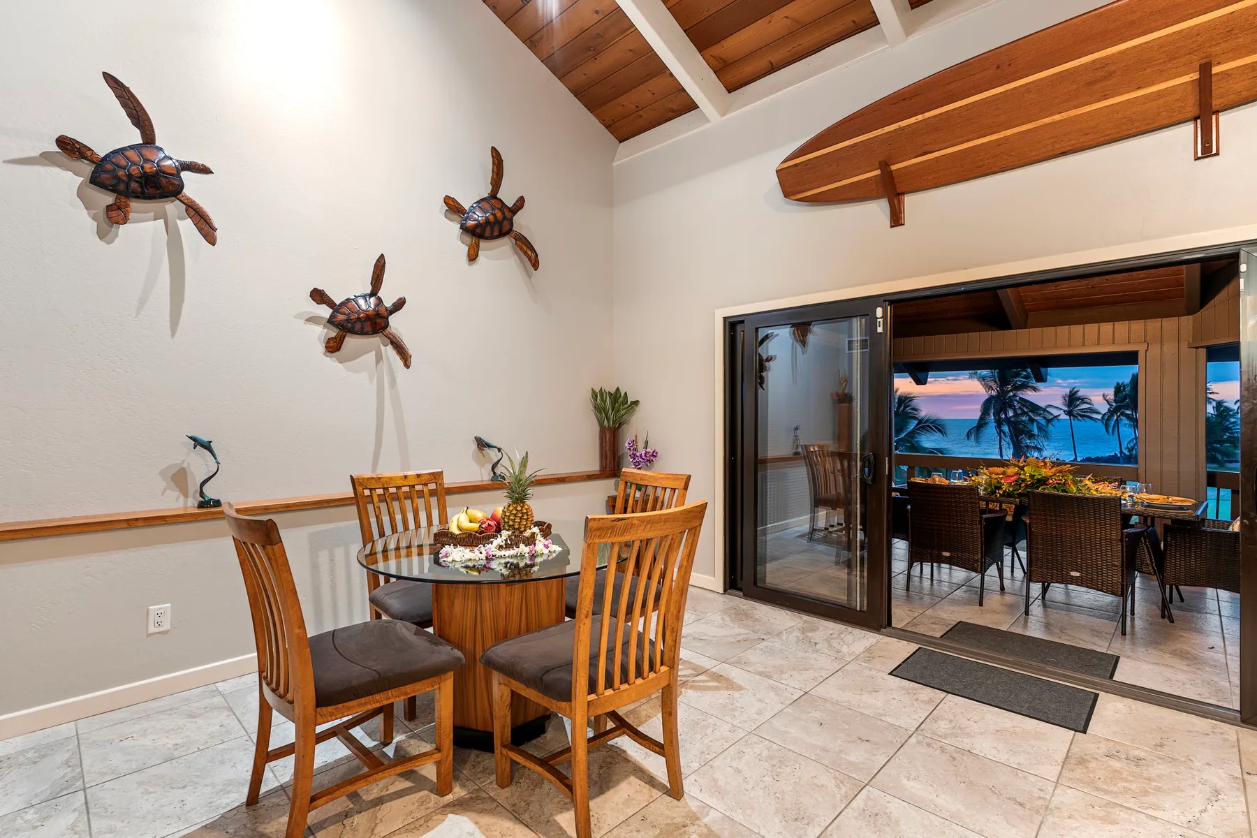 Comedor con mesa de madera y asientos junto a puertas corredizas abiertas.