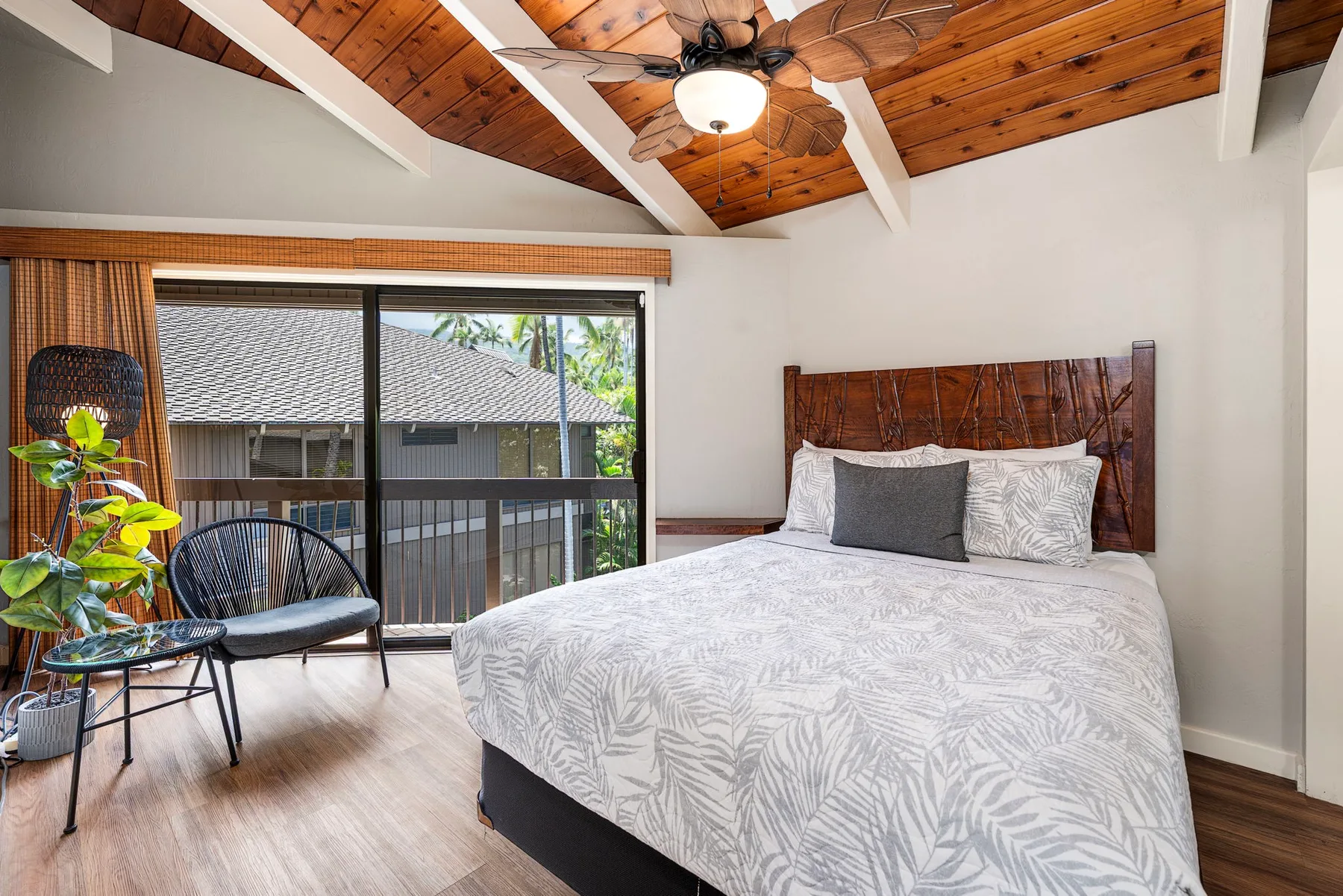 Un dormitorio con una cama bajo un techo abovedado de madera y un ventilador de techo.