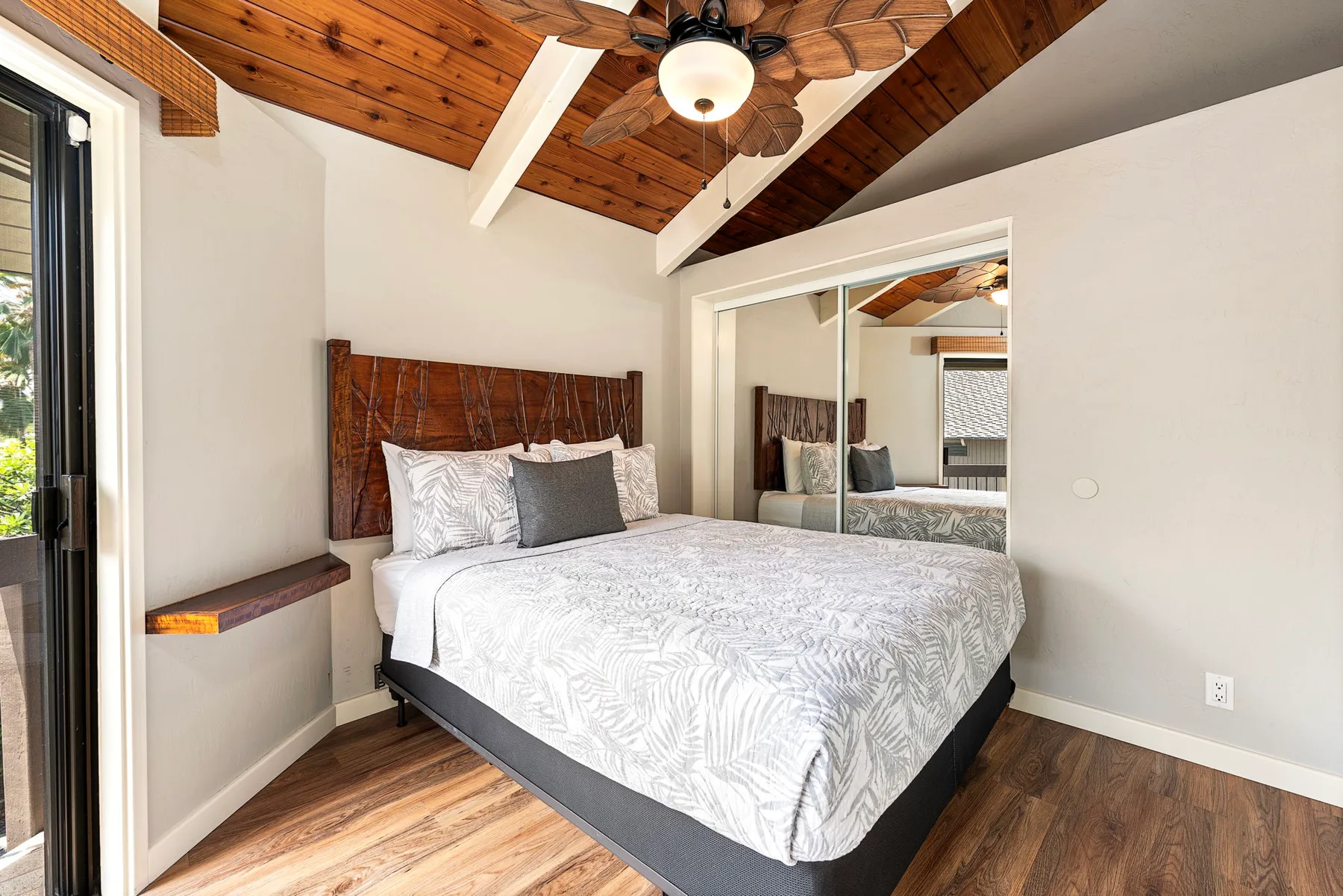 Un dormitorio con una cama bajo un techo revestido de madera y un ventilador.