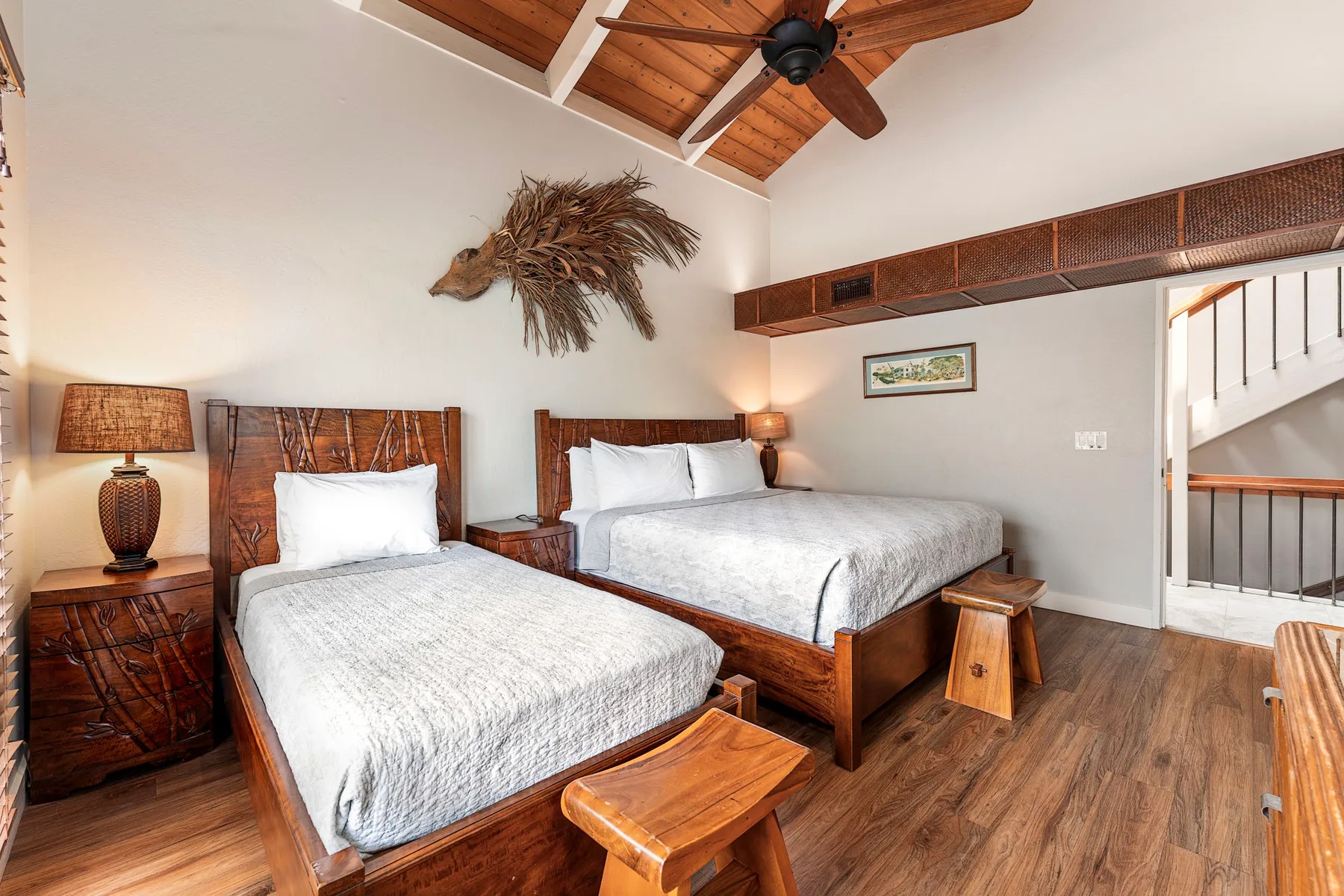 Dormitorio con dos camas de madera bajo un techo abovedado de madera.