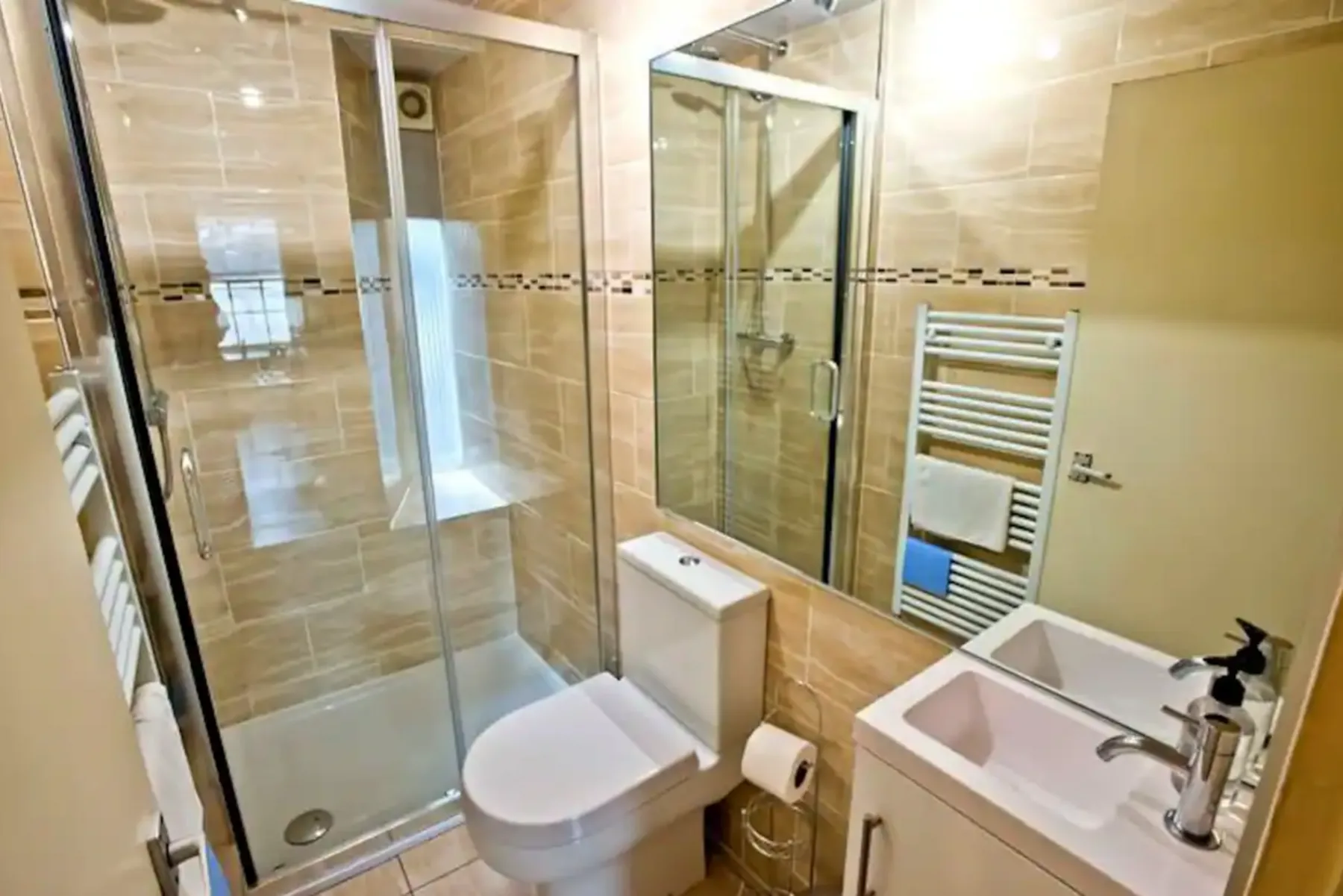 A tiled bathroom with a glass shower, toilet, and sink.