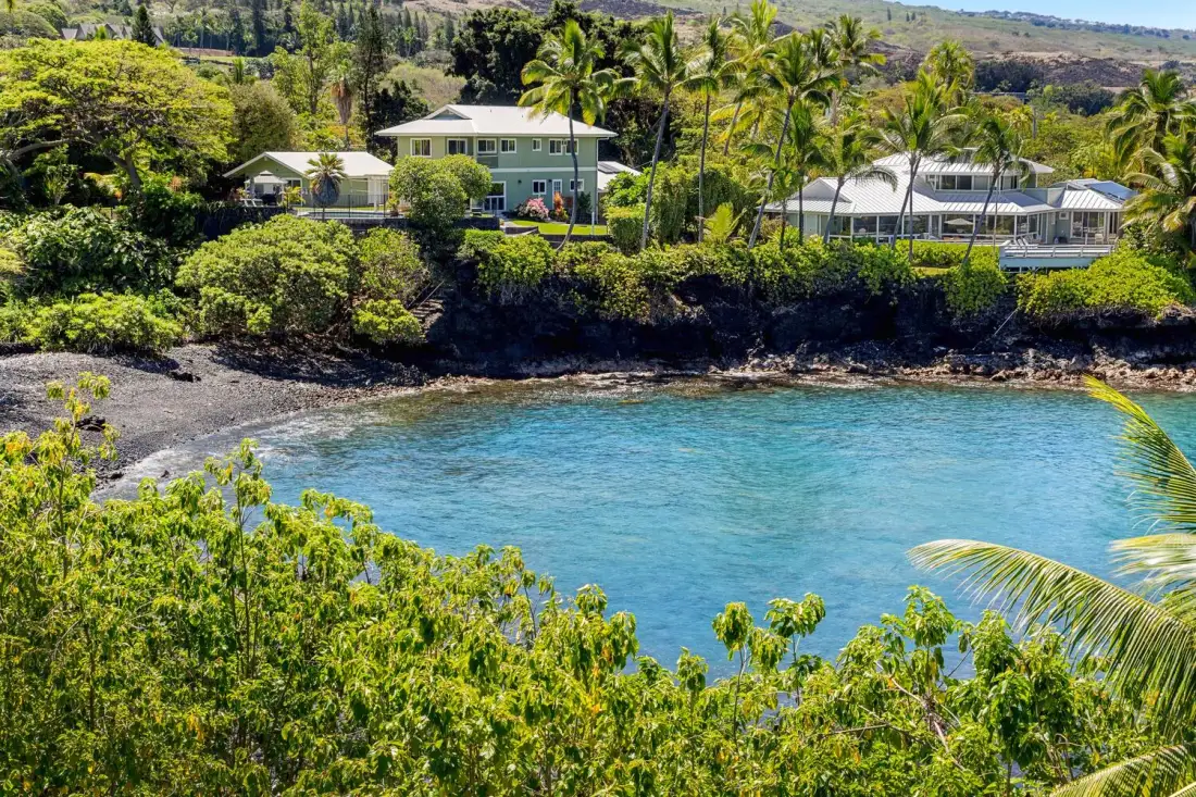 Una bahía protegida con agua azul clara, vegetación tropical y edificios junto a la costa.