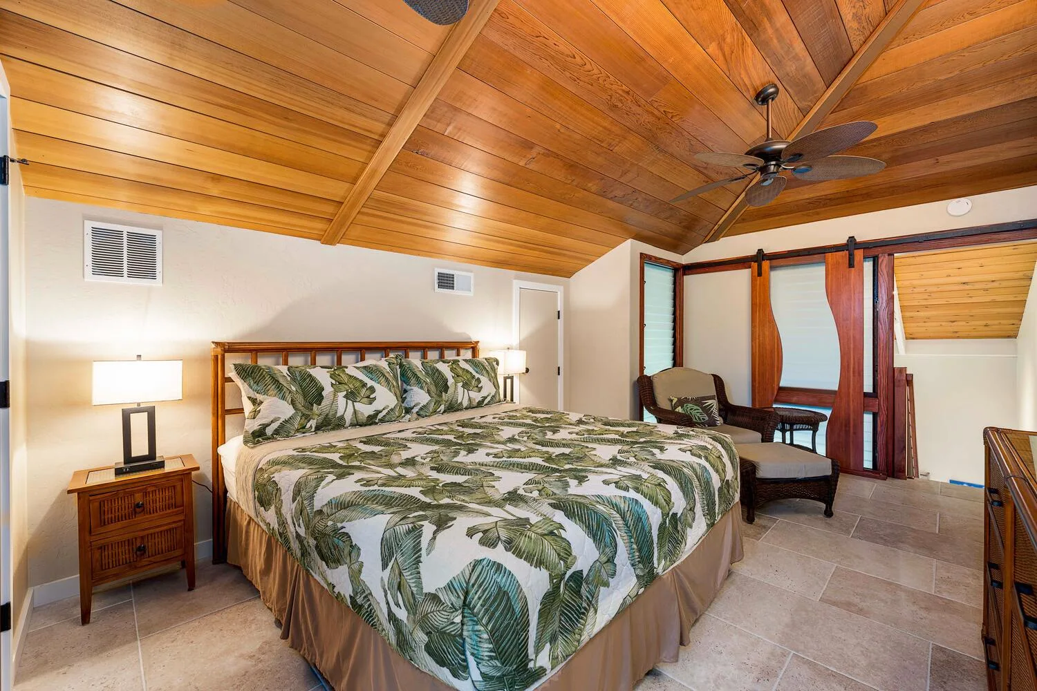 Un dormitorio con una cama grande bajo un techo inclinado revestido de madera.