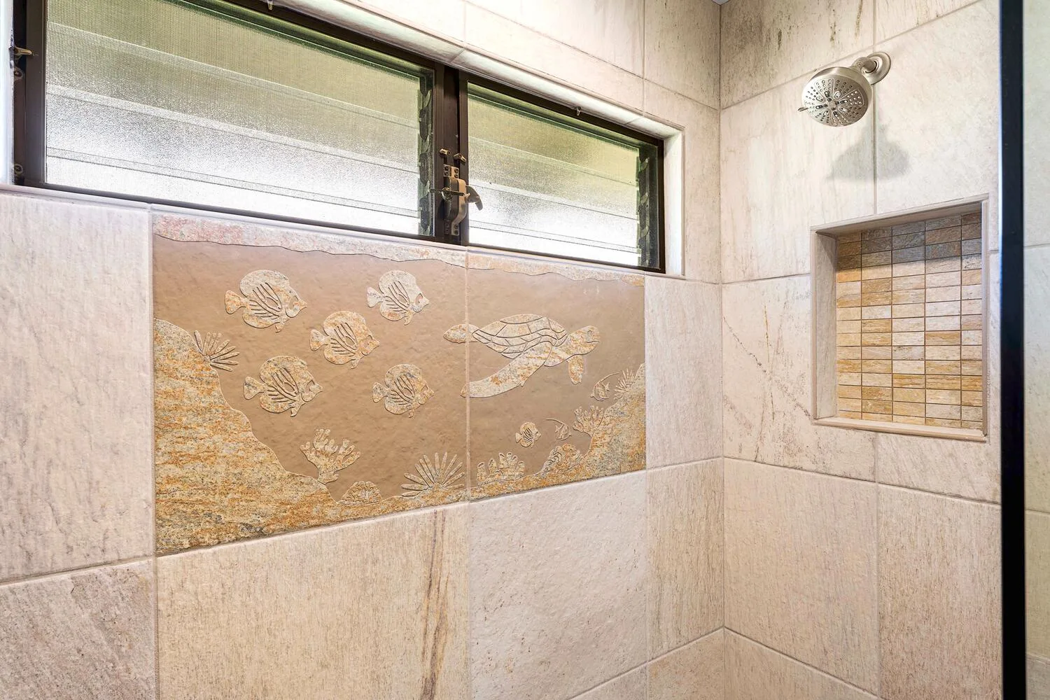 Una zona de ducha alicatada tiene un panel decorativo con peces y un nicho.