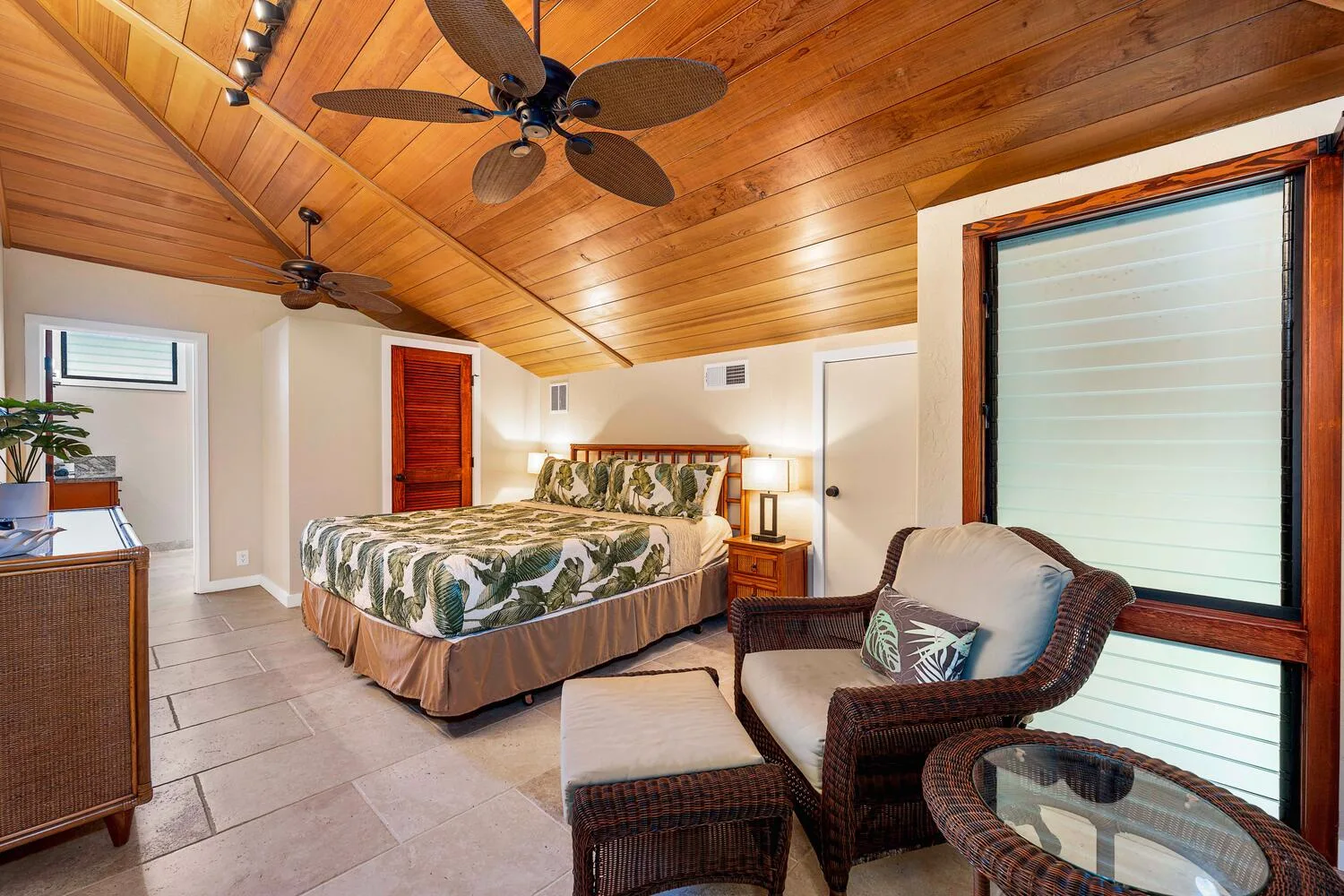 Un dormitorio con una cama grande y una zona de estar bajo un techo de madera.