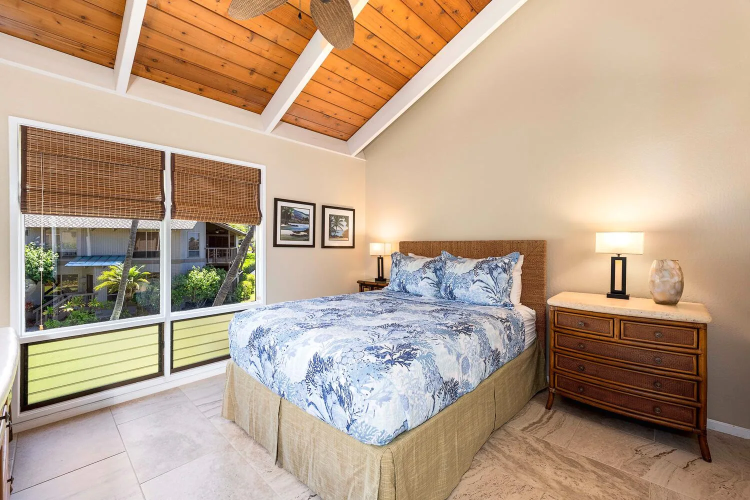 Un dormitorio con una cama vestida con ropa de cama azul y blanca y una cómoda de madera.