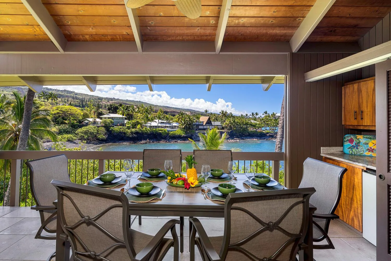 Una zona cubierta de comedor al aire libre da a un río, con la mesa preparada para comer.