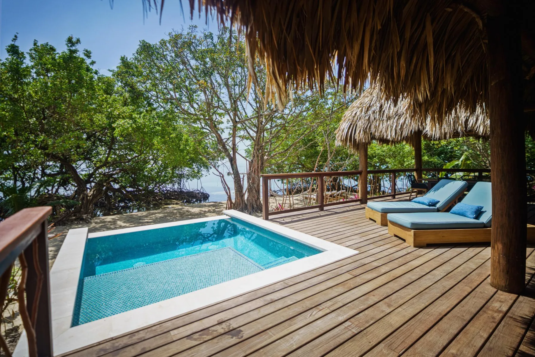 A small pool sits beside a wooden deck with cushioned lounge seating.