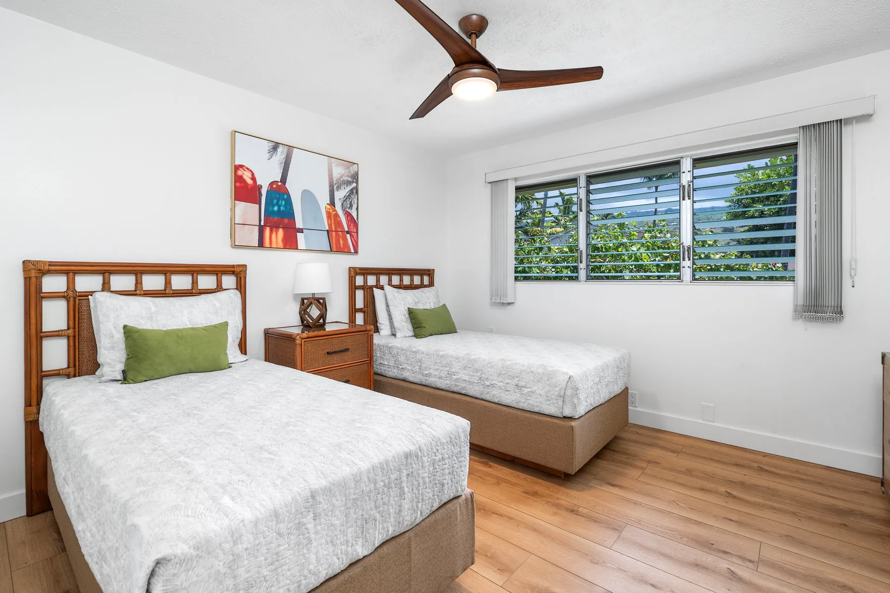 A bright bedroom with two beds and a wide window.