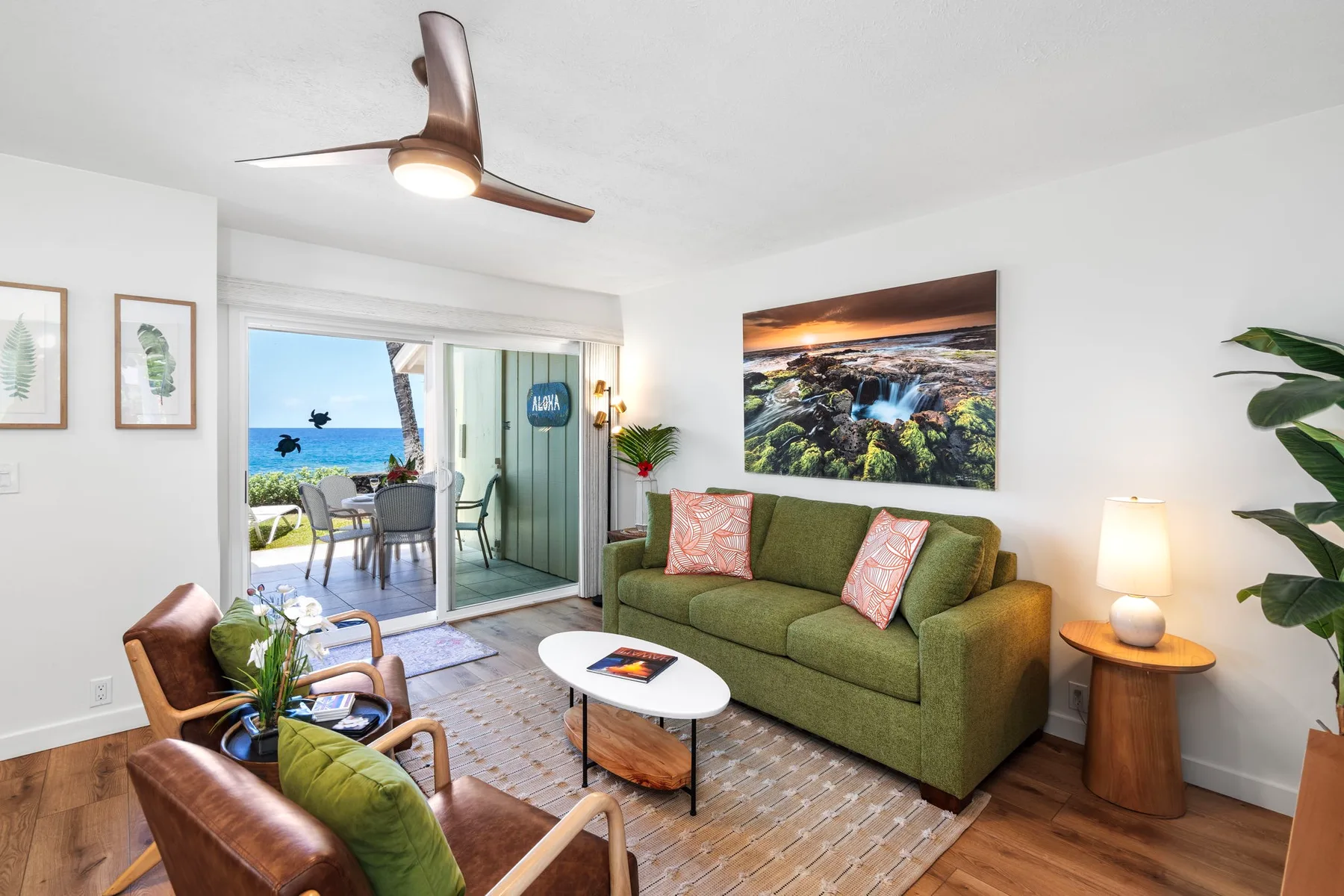 A living room with green seating and sliding glass doors opening onto a balcony.