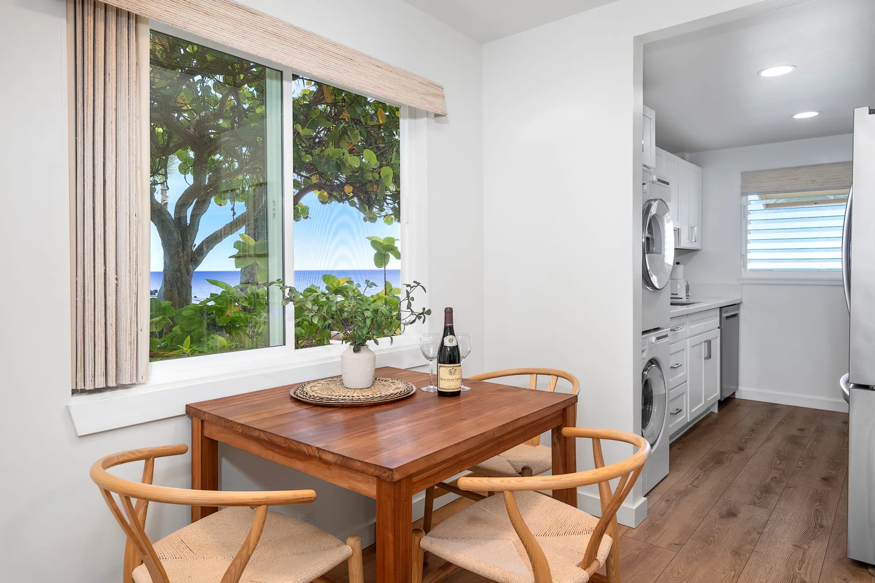 A dining area with a wooden table beside a window overlooking greenery and water.