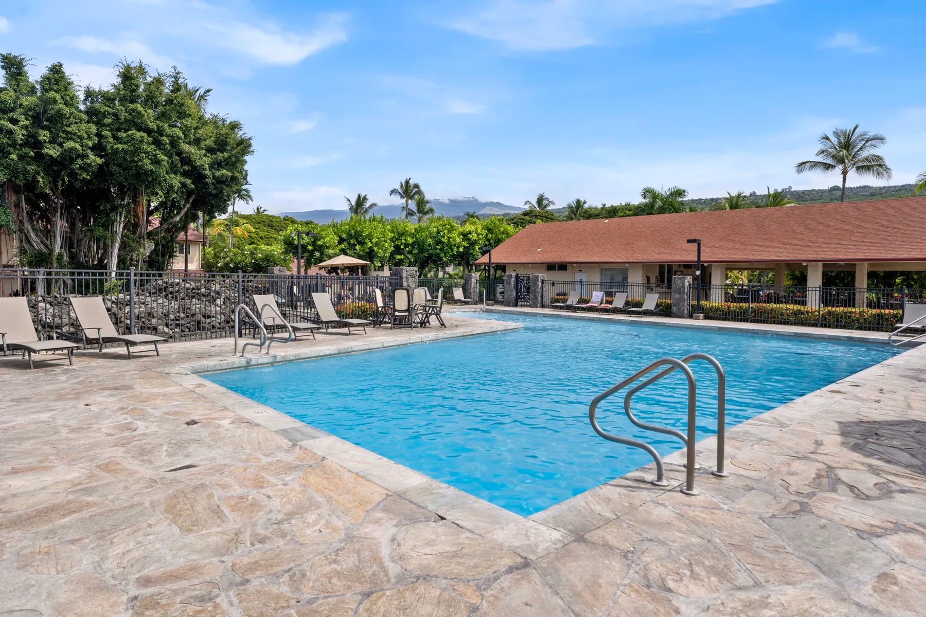 An outdoor swimming pool is surrounded by a paved deck and seating.