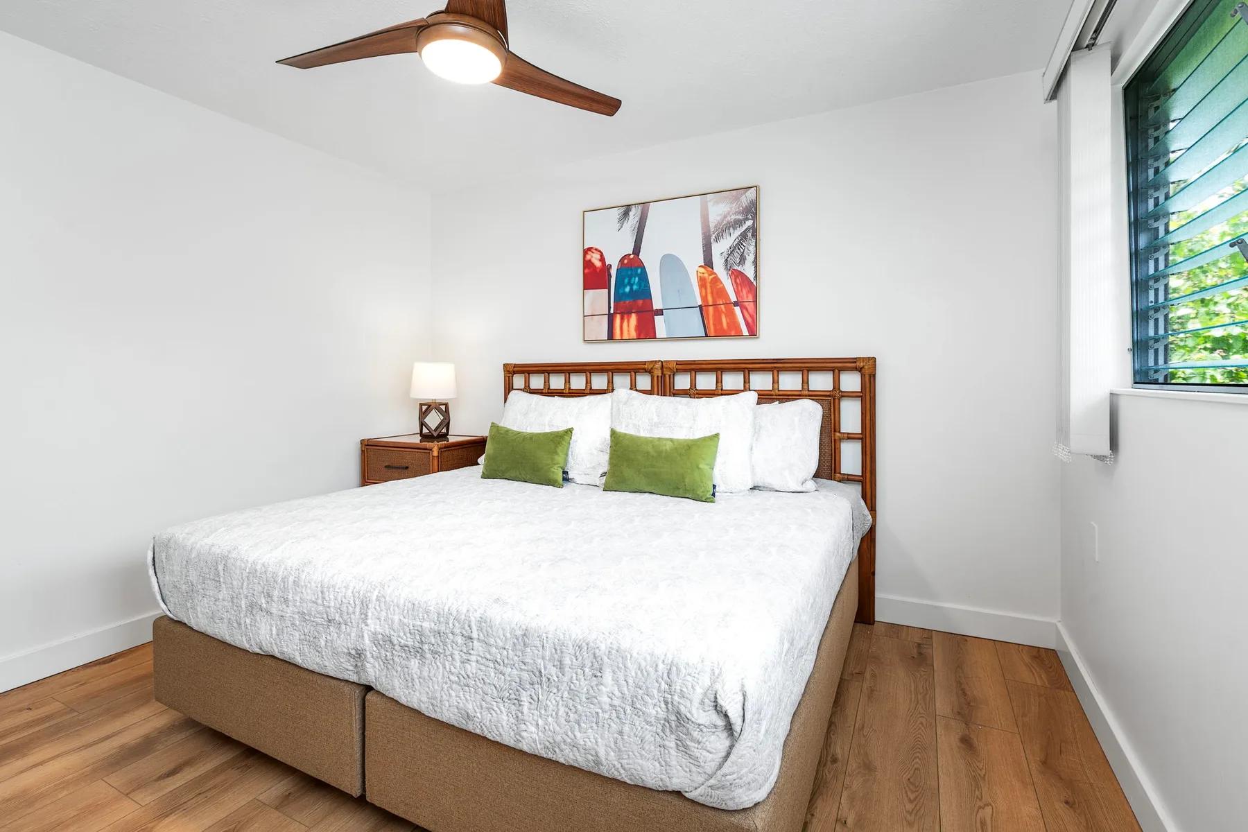 A bright bedroom with a bed, bedside table, and window.